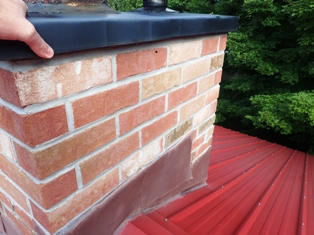 Home and cottage inspection in muskoka, Gravenhurst, Bracebridge, Balla, Port Carling and Huntsville includes roofing inspections where we walk most roofs to get the most detailed inspection possible. Here our inspector is checking a chimney cap and flashing. Inspector is on roof looking at flashing around chimney